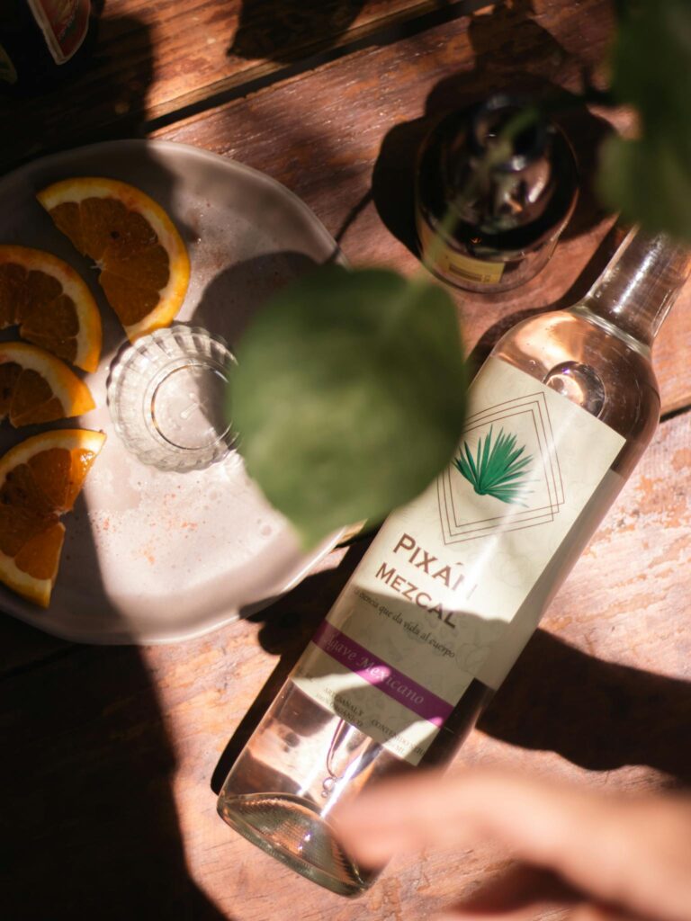 A creative shot of mezcal with sliced oranges on a rustic table.